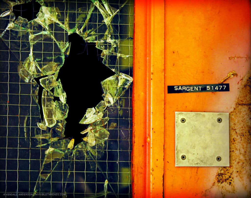 Broken wire glass is beside a bright orange door and frame. The door has a label reading 'Sargent 51477'.