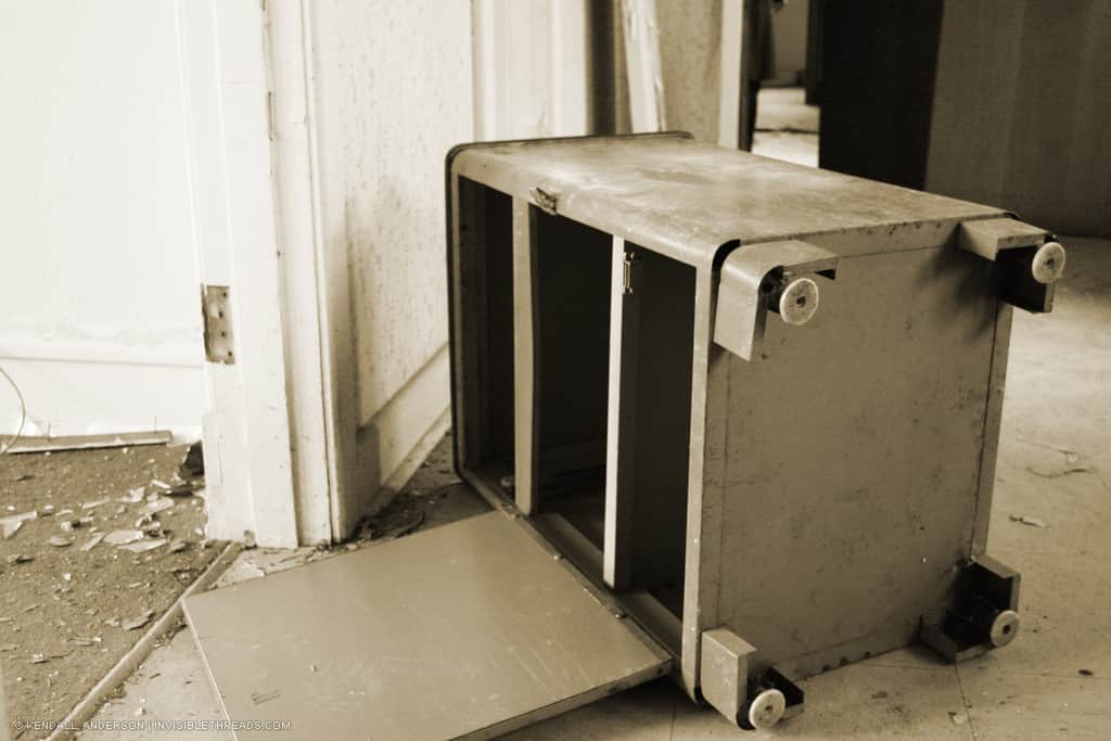 A metal cabinet is overturned and lying on the floor.