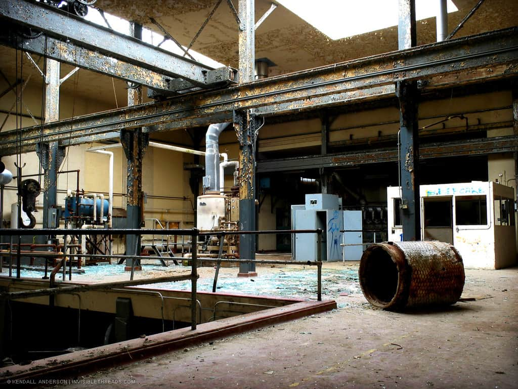 A long steel beam runs through an industrial building. Mechanical equipment is behind a series of steel columns.