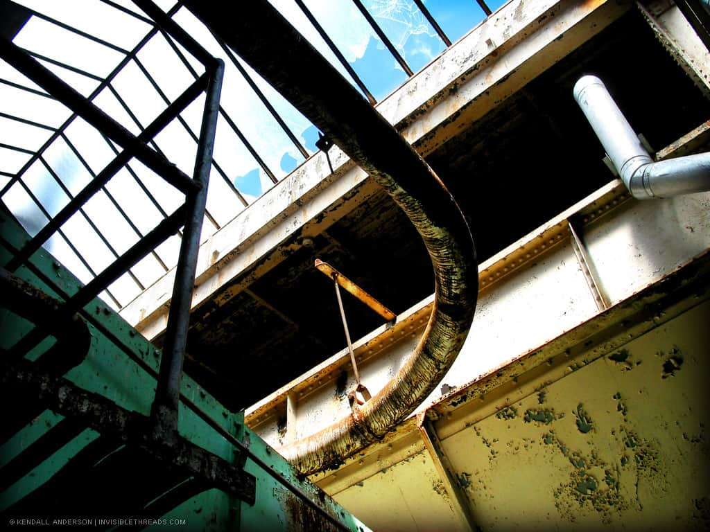 A curved air duct is hanging below a large skylight in a mechanical room.