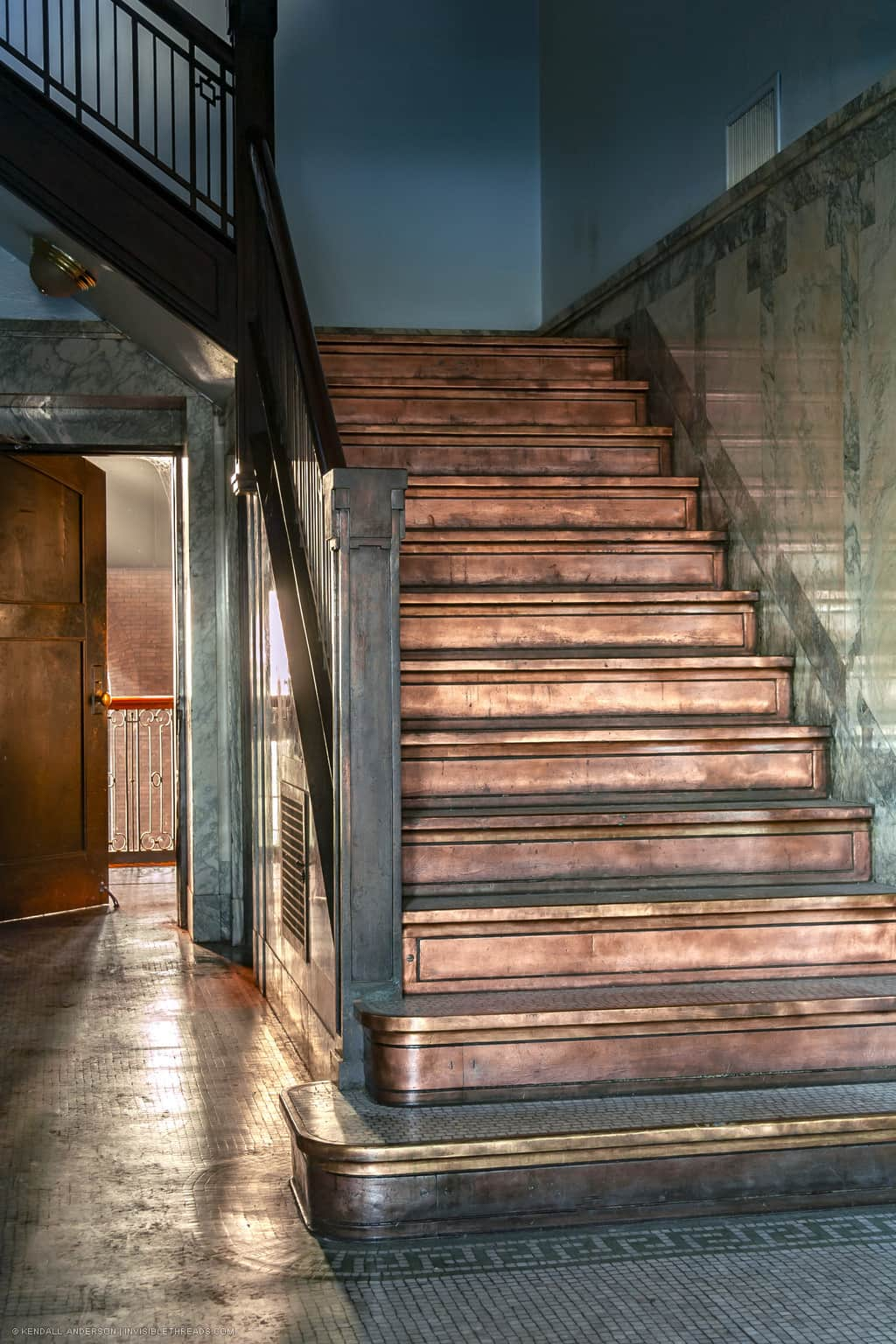 A set of stairs leads up to another level. The floor and stair treads are covered in mosaic tile. The stair risers are solid copper.